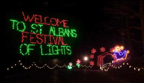 Colorful holiday lights display reading "Welcome to St. Albans Festival of Lights" with festive decorations.