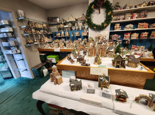 A display of intricate miniature houses and holiday decorations in a cozy shop setting.