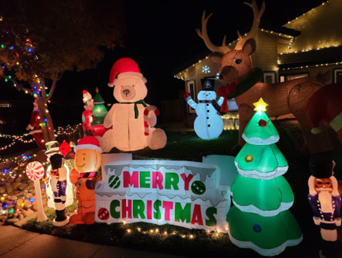 Colorful Christmas decorations featuring inflatable characters, a tree, and a "Merry Christmas" sign in a festive display.