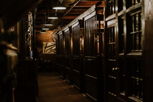 Dimly lit hallway with wooden partitions and a cozy, rustic atmosphere in a restaurant.