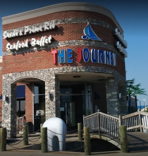 Exterior of a restaurant named "The Journey," featuring a brick facade and a wooden walkway leading to the entrance.