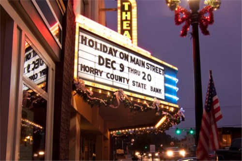 Marquee of a theater displaying "Holiday on Main Street" from Dec 9 to 20, with festive decorations and an American flag.