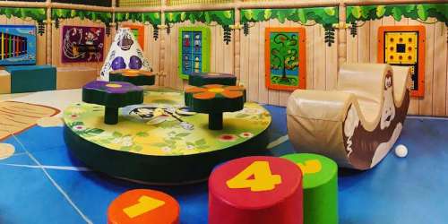 Colorful indoor play area with interactive toys, numbered blocks, and a soft seating area for children.
