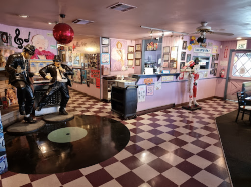 A colorful diner interior featuring statues of musicians, retro decor, and a checkered floor.