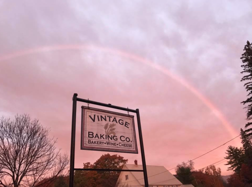 A sign for Vintage Baking Co. with a rainbow and pink sky in the background.