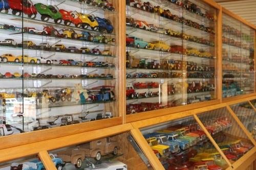 A display case filled with various colorful toy cars arranged neatly on shelves.
