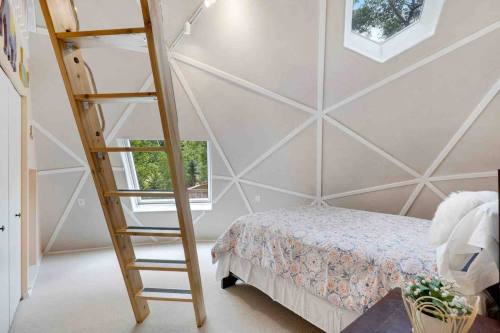 Cozy bedroom with a unique geometric ceiling, a ladder, and a bed adorned with a colorful quilt.