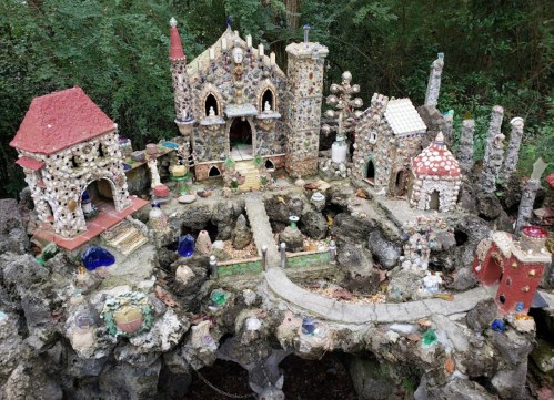 A whimsical miniature village made of stones and shells, featuring various colorful buildings and pathways.