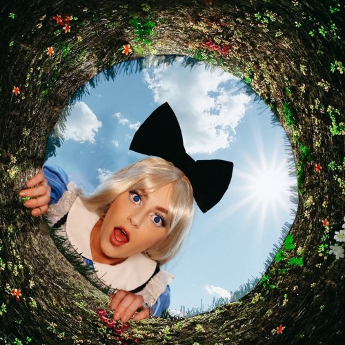 A surprised girl in a blue dress and large bow peers down a colorful, flower-lined hole with a bright sky above.