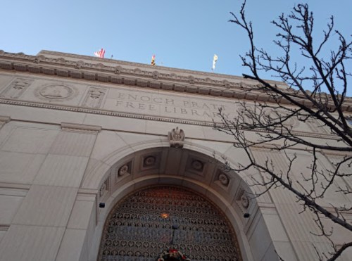 View of the Enoch Pratt Free Library entrance, featuring ornate architecture and a clear blue sky.