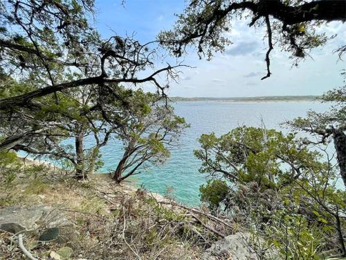 A serene view of a lake surrounded by trees and rocky shoreline under a partly cloudy sky.