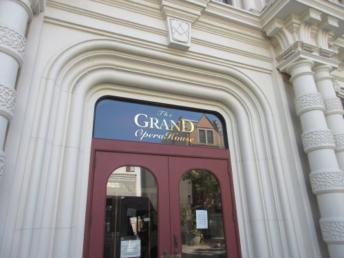 Entrance of a building featuring an ornate archway and a sign that reads "The Grand Open House."