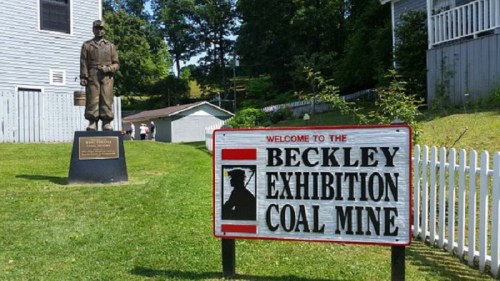 A statue of a miner stands beside a sign welcoming visitors to the Beckley Exhibition Coal Mine.