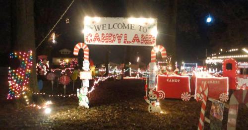A festive entrance to "Candyland" decorated with colorful lights, candy-themed decorations, and a welcoming sign.