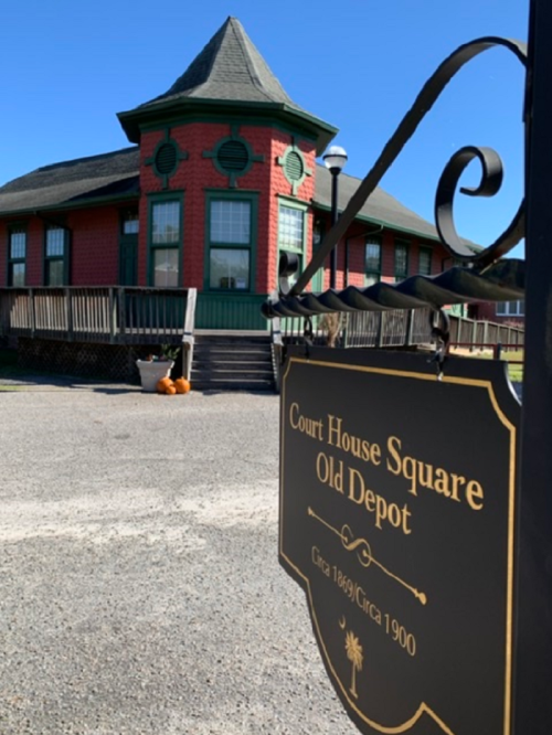 Historic red and green building with a pointed roof, featuring a sign for "Court House Square Old Depot."