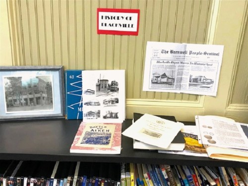 A display of historical materials about Blackville, including photos, books, and newspapers on a table.