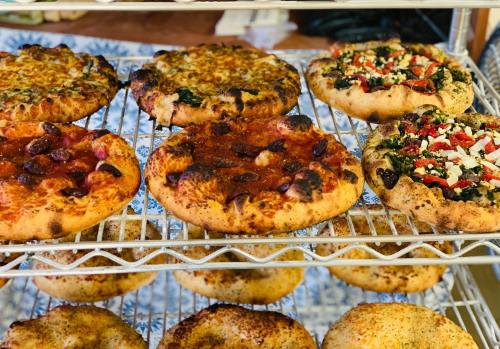 A variety of freshly baked pizzas on a wire rack, featuring different toppings and crusts.