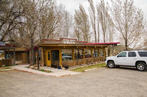 A rustic restaurant named "Burr Trail Grill" with large windows, surrounded by trees and a parked white SUV.