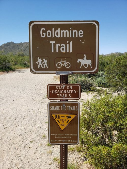 Sign for Goldmine Trail with icons for biking and horseback riding, and a reminder to share the trails.