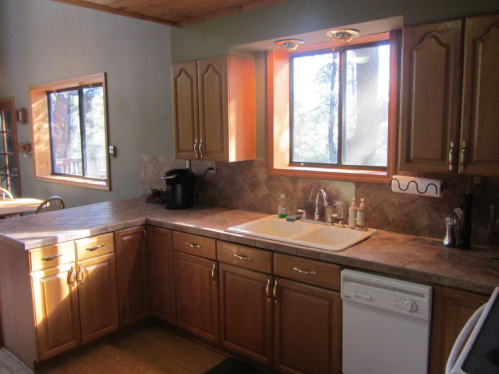 Bright kitchen with wooden cabinets, a sink, and a window letting in natural light. Countertop appliances are visible.