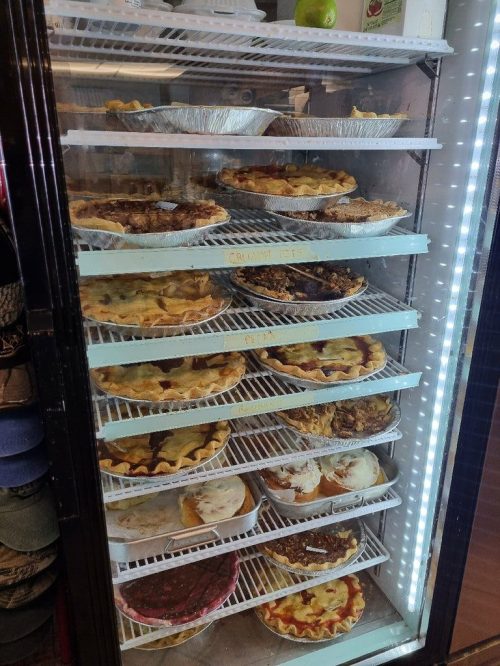A display case filled with various types of pies, showcasing different flavors and crust designs.