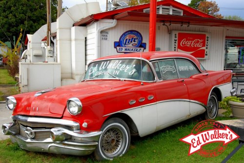 A vintage red and white car parked outside Ed Walker's Drive-In, featuring retro signage and a nostalgic atmosphere.