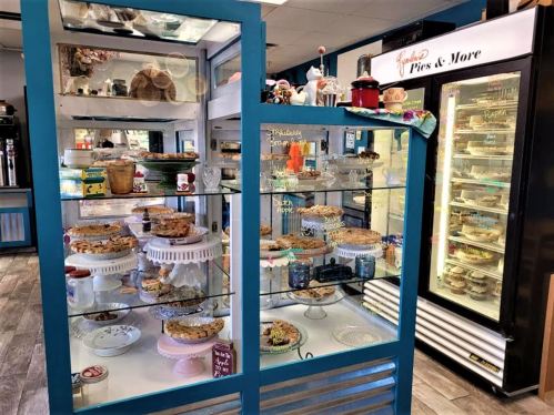 Display case filled with various baked goods, including pies and cookies, in a cozy bakery setting.