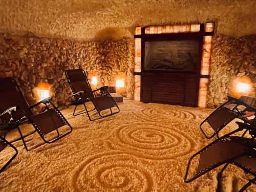 A cozy salt room with reclining chairs, warm lighting, and a salt wall, creating a relaxing atmosphere.