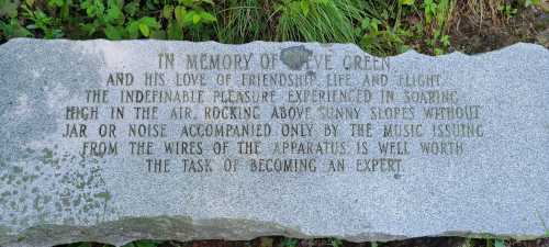 A stone memorial inscribed with a tribute to E. Green, celebrating friendship and the joy of soaring in the air.