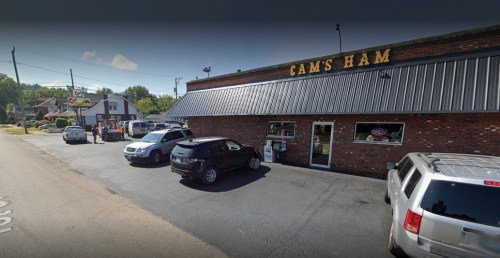 Exterior view of Cam's Ham restaurant with parked cars and a clear blue sky. Signage visible on the building.