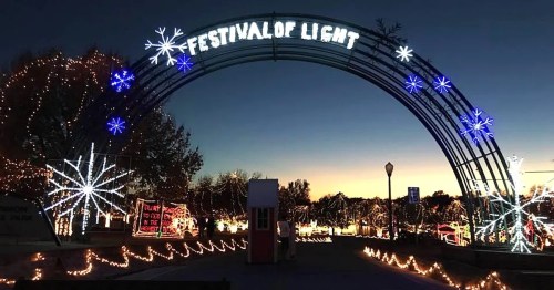 A festive archway reading "Festival of Light" adorned with colorful lights against a twilight sky.