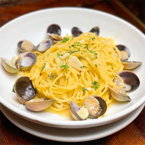 A bowl of spaghetti with clams, garlic, and parsley, garnished with sliced almonds.