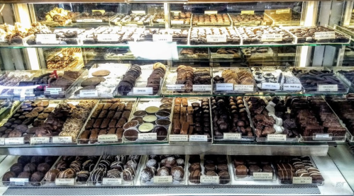 A display case filled with a variety of chocolates and confections, neatly arranged on glass shelves.