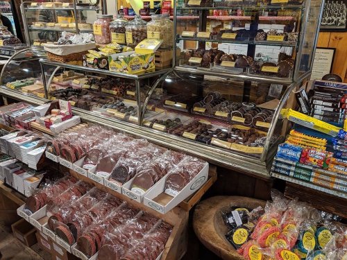 A display of assorted chocolates and candies in a shop, featuring various packaged treats and jars of sweets.