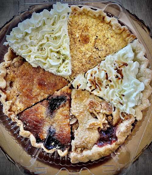 A pie divided into six sections, each with different toppings and fillings, including cream, fruit, and nuts.
