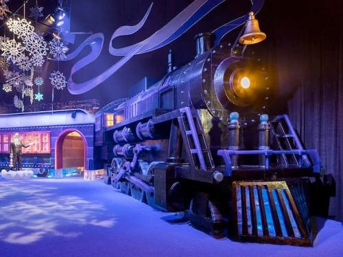 A festive train display surrounded by snowflakes and winter decorations in a colorful setting.
