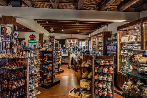 A vibrant gift shop filled with shelves of colorful crafts, pottery, and souvenirs, with customers browsing inside.