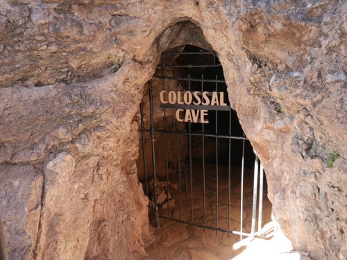 Entrance to Colossal Cave, featuring a metal gate set in a rocky cave opening.