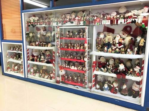 A display case filled with various festive holiday decorations, including Santa figures and other Christmas-themed items.