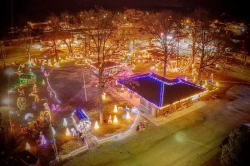 Aerial view of a festive park illuminated with colorful holiday lights and decorations at night.