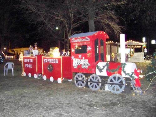 A festive train display decorated for the holidays, featuring lights and a "North Pole Express" sign.