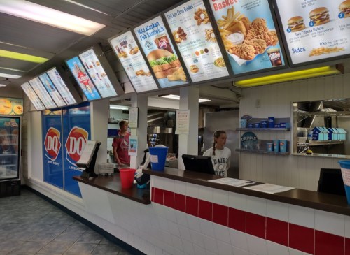 Interior of a fast-food restaurant with menu boards, a counter, and staff members preparing orders.
