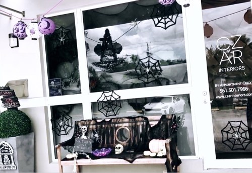 A storefront decorated for Halloween with spider webs, a skeleton, and purple accents.