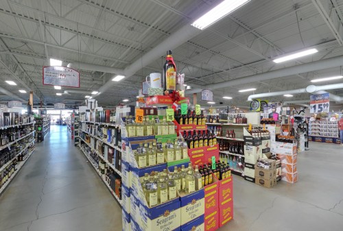 A spacious liquor store aisle with shelves stocked with various bottles and a prominent display in the center.