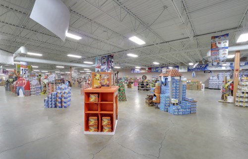 A spacious retail store interior with shelves of products, displays, and bright overhead lighting.