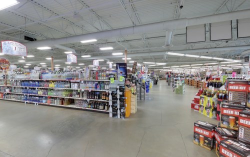 A spacious retail store aisle filled with shelves of various beverages and products, including beer and wine.