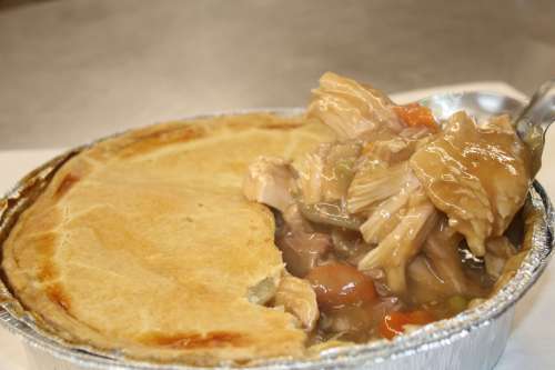A close-up of a chicken pot pie with a golden crust, revealing tender chicken and vegetables inside.