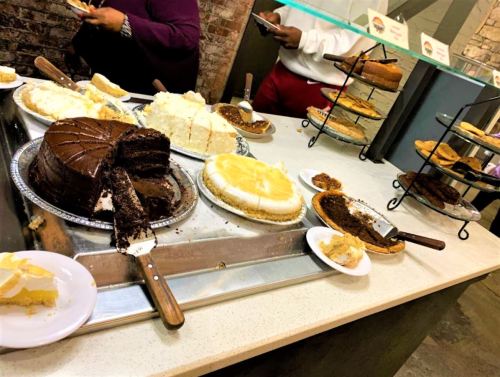 A variety of desserts displayed on a table, including chocolate cake, cheesecake, and assorted cookies.