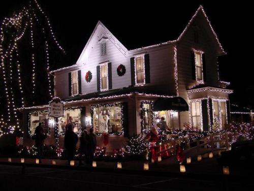 A beautifully decorated house with festive lights and wreaths, surrounded by glowing lanterns and holiday decorations.