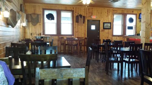 Cozy wooden interior of a restaurant with empty tables and chairs, featuring rustic decor and large windows.